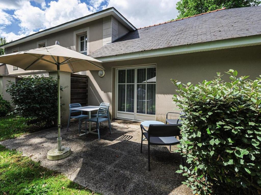 une terrasse avec une table, des chaises et un parasol dans l'établissement Holiday home Club Le Domaine Du Golf 2, à Saint-Hilaire-Saint-Florent