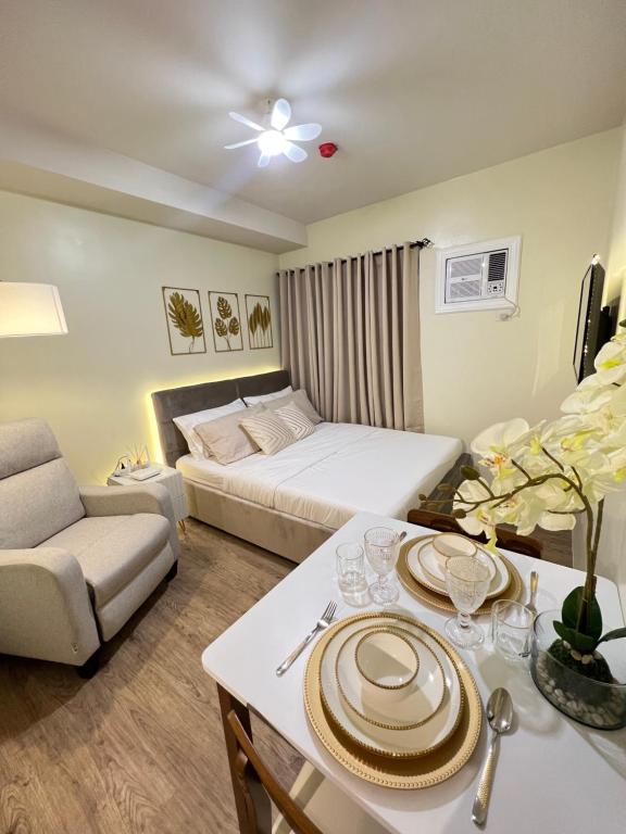 Cette chambre d'hôtel comprend un lit et une table avec des assiettes. dans l'établissement Condo near Nuvali Laguna Technopark St Benedict Church, à Bayabasan