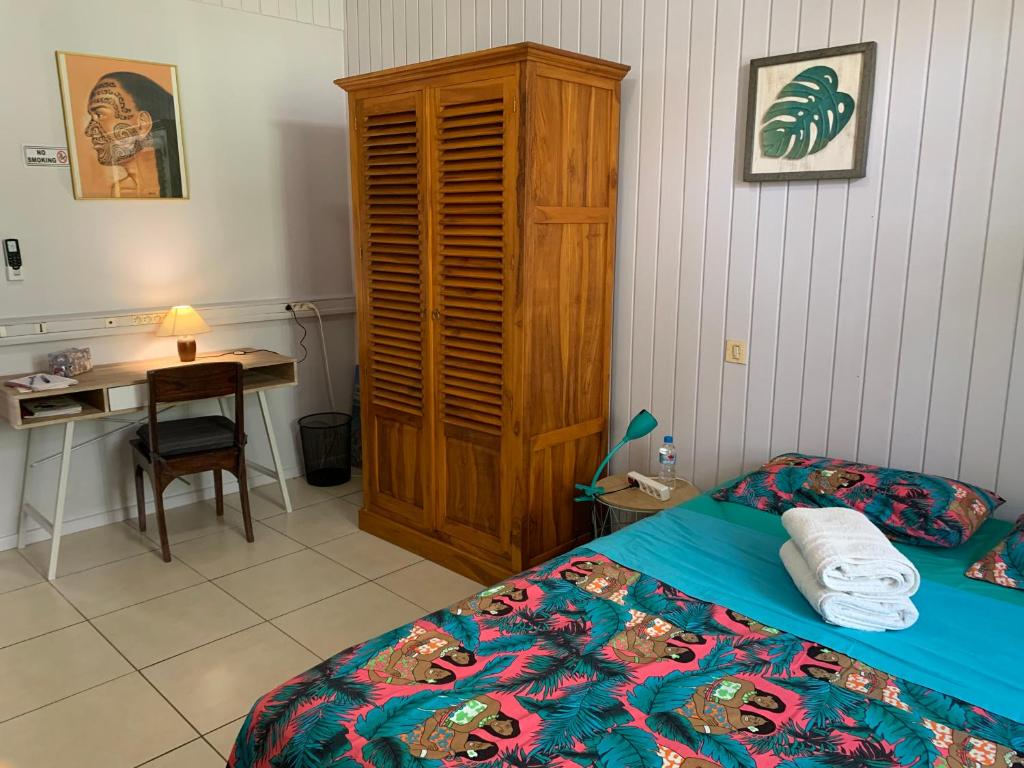a bedroom with a bed with a wooden cabinet and a desk at City Home Tahiti in Papeete