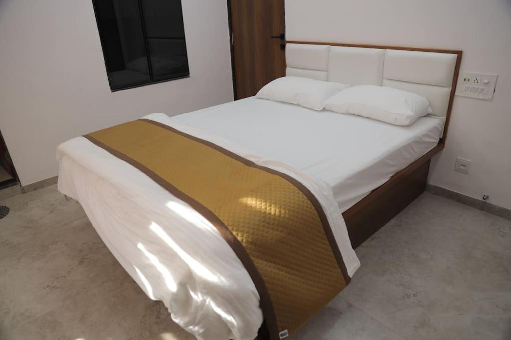 a bedroom with a large bed with white sheets at Gulmohar Homes in Udaipur