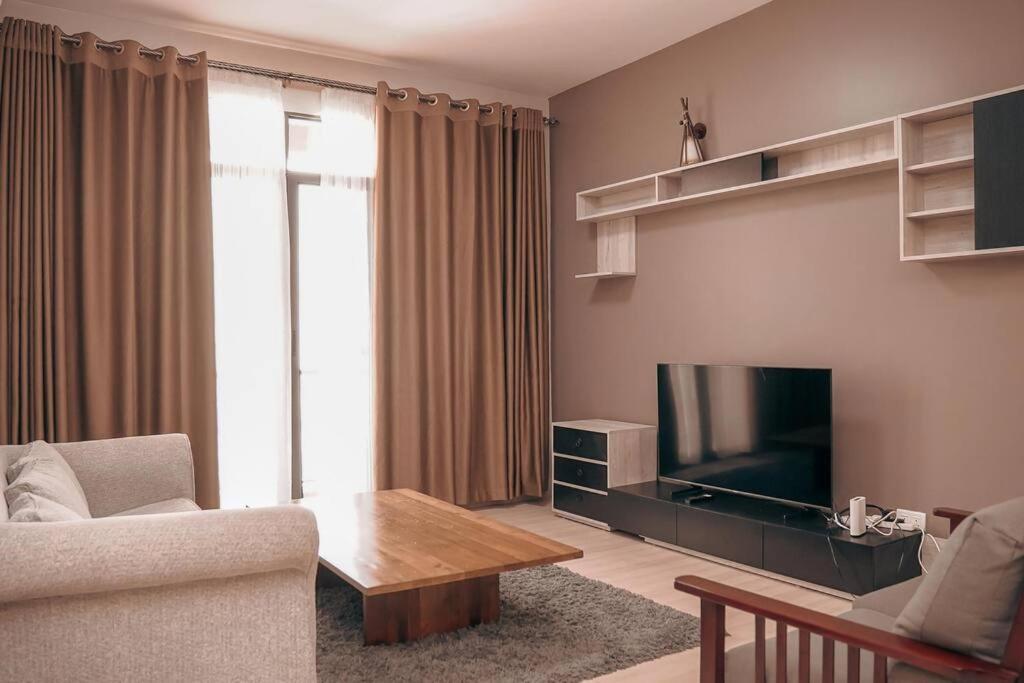 ein Wohnzimmer mit einem Sofa und einem TV in der Unterkunft Charming Waterside Escape in Entebbe
