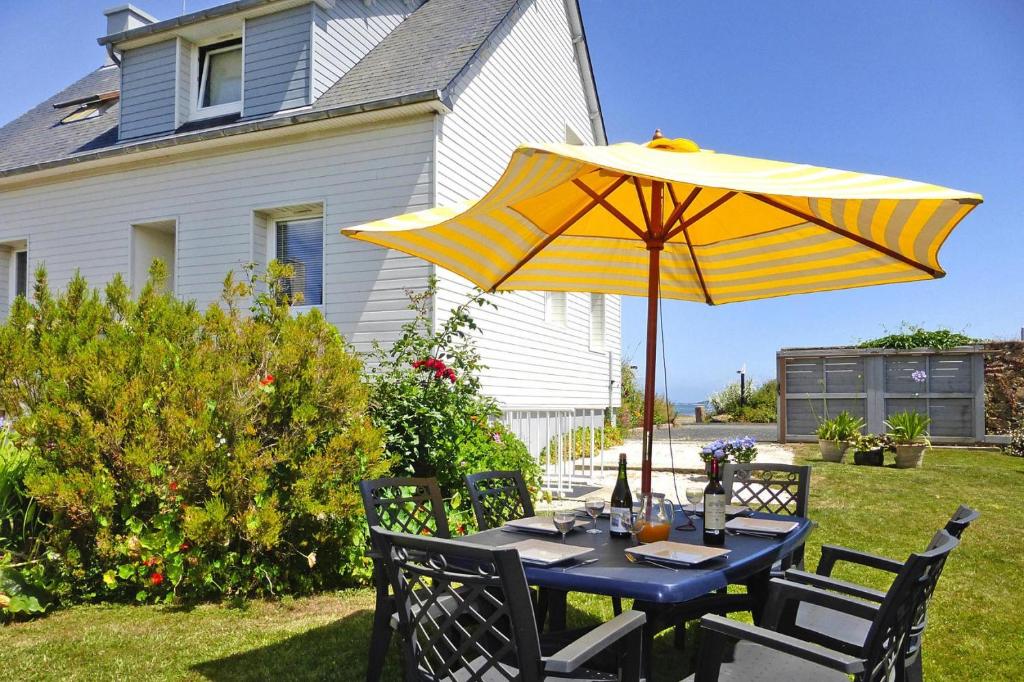 a blue table with a yellow umbrella on a yard at Holiday home in Perros Guirec in Perros-Guirec