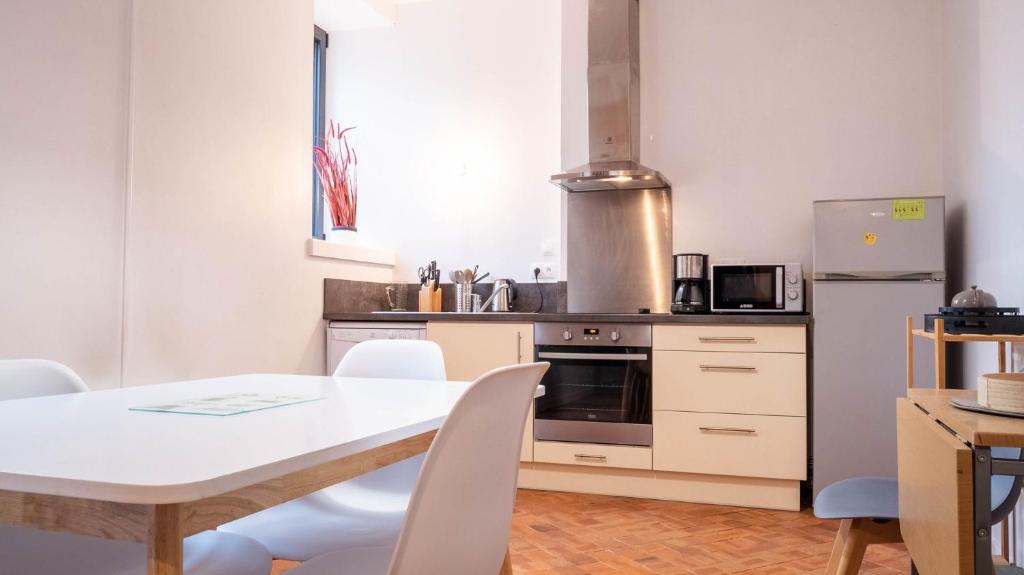 eine Küche mit einem Tisch und Stühlen sowie einem Kühlschrank in der Unterkunft Le Moulin du Clain - Jolie maison à Poitiers in Poitiers