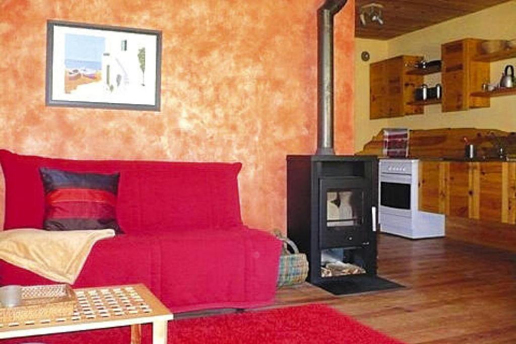 a living room with a red couch and a stove at Apartment in a charming location on Forellenhof Zorn Valley Dabo in Dabo