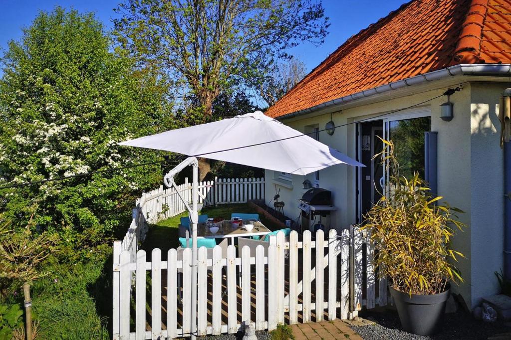 una cerca blanca con un paraguas blanco al lado de una casa en Holiday home in Criel sur Mer near sea en Criel-sur-Mer