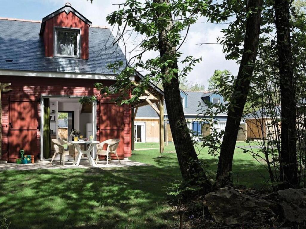 une maison rouge avec une table et des chaises dans la cour dans l'établissement Holiday home Club Le Domaine Du Golf 1, à Saint-Hilaire-Saint-Florent