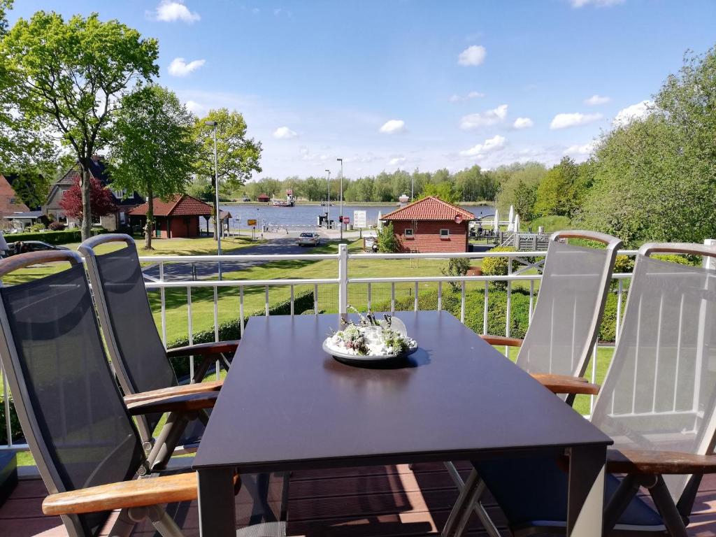 a table and chairs on a balcony with a view of a river at Villa Kanalblick, Ausguck in Oldenbüttel