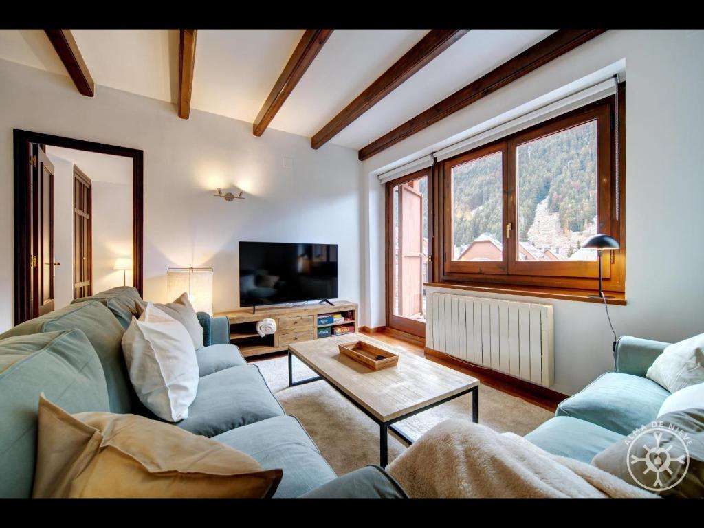 a living room with a blue couch and a tv at MOW'S SNOW LODGE BAQUEIRA de Alma de Nieve in Naut Aran