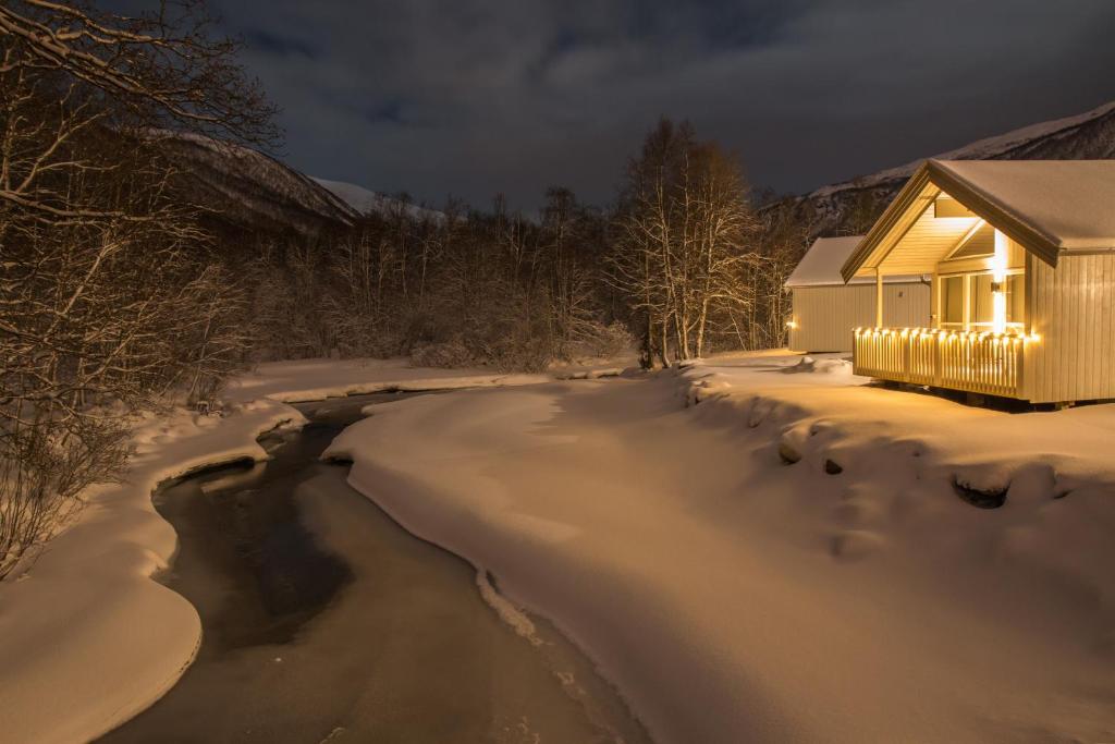 a house in the snow with lights on it at Tromsø Lodge & Camping in Tromsø