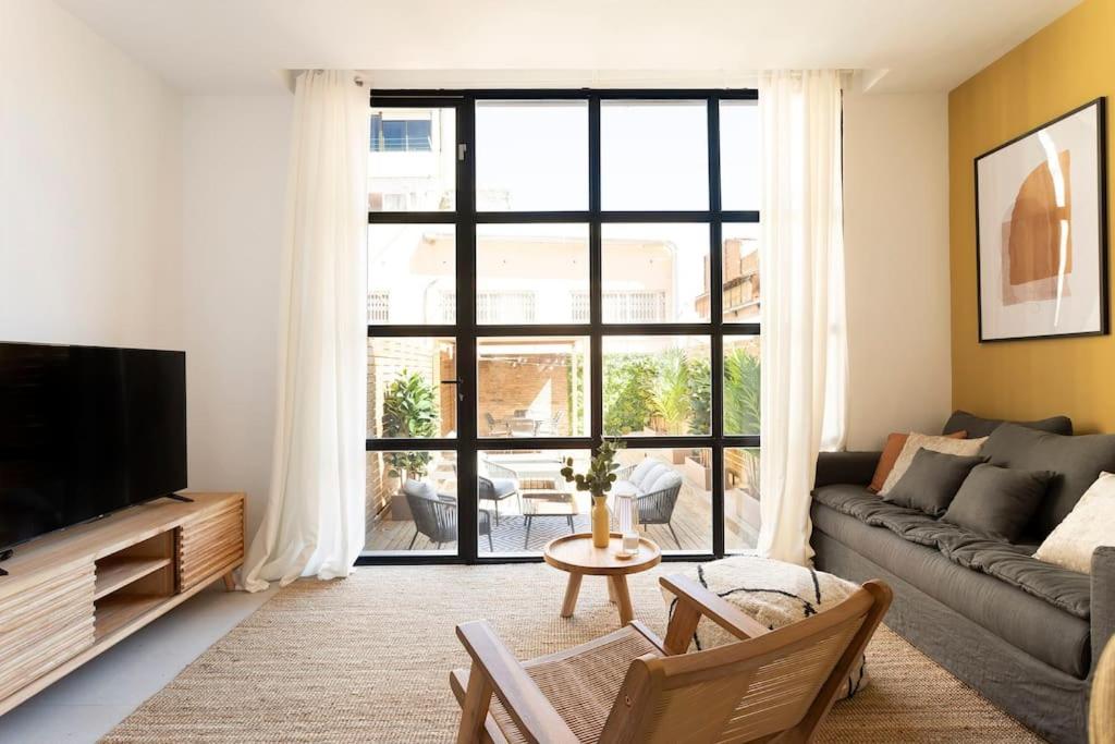 een woonkamer met een bank en een groot raam bij Lodging Apartments Rambla Poblenou 12 in Barcelona