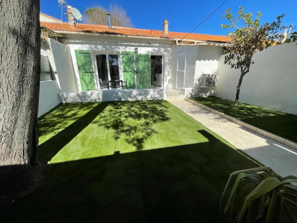 une maison avec une cour avec de l'herbe verte dans l'établissement Petite Maison à la Loubiere avec jardin, clim et parking, à Toulon