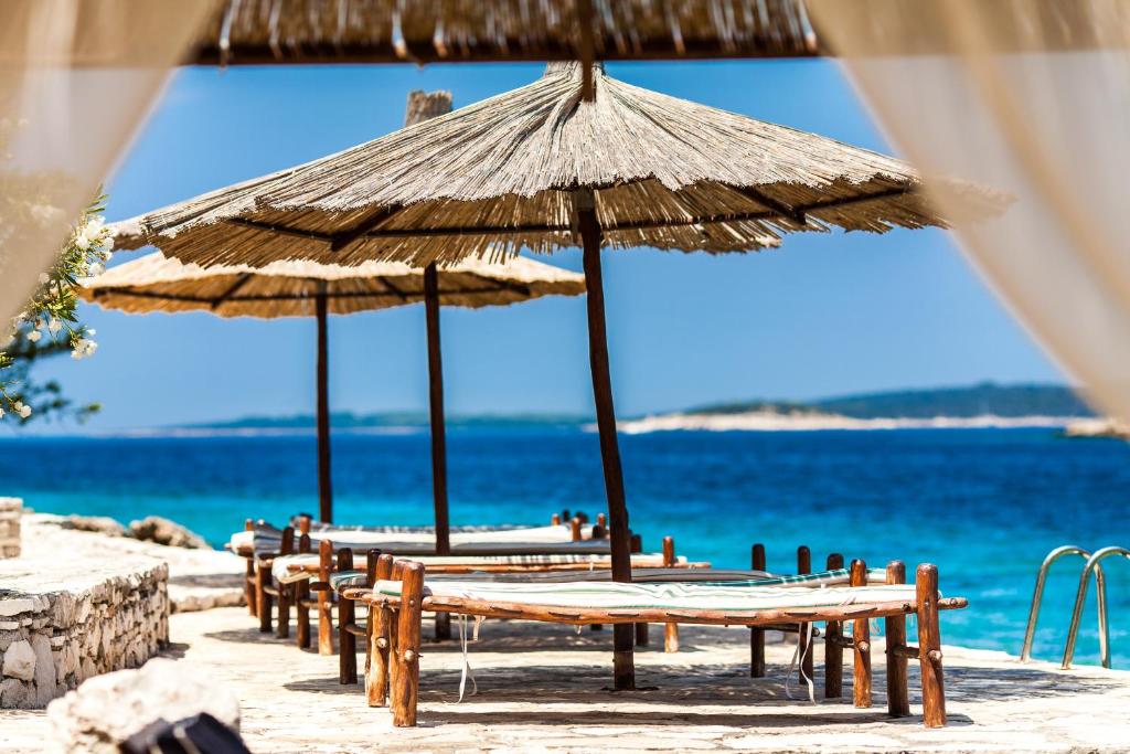 Holiday Home Sunny Side في فيلا لوكا: مجموعة طاولات ومظلات على الشاطئ