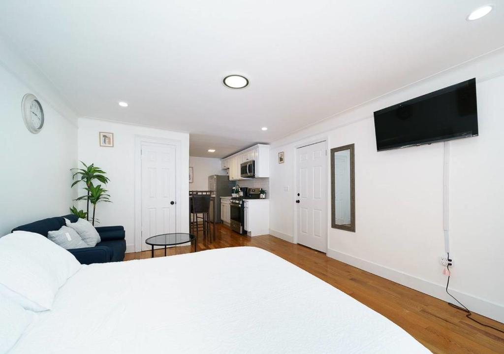 ein weißes Schlafzimmer mit einem Bett und einem TV an der Wand in der Unterkunft Comfy Studio in UES! Perfect for 2! in New York