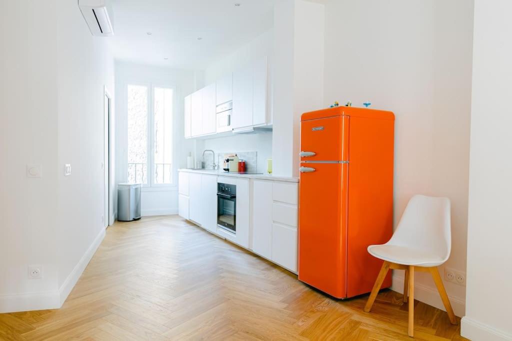 - un réfrigérateur orange dans une cuisine blanche avec une chaise dans l'établissement Spectacular 1B apartment - French Riviera (port), à Nice