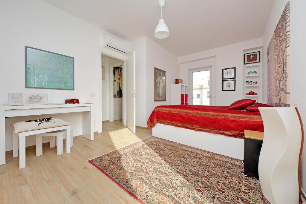 a white bedroom with a red bed and a table at Vista Borgo - Lusso a Ostia Antica con Self Checkin e Free WIFI in Ostia Antica