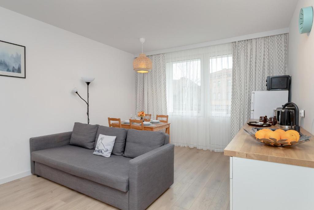 a living room with a gray couch and a kitchen at Apartments Łagiewniki Gdańsk by Renters in Gdańsk