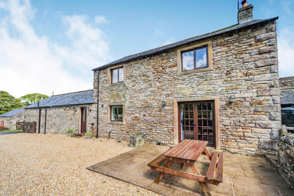 ein Steinhaus mit einem Picknicktisch davor in der Unterkunft The Stable in Crosby Ravensworth