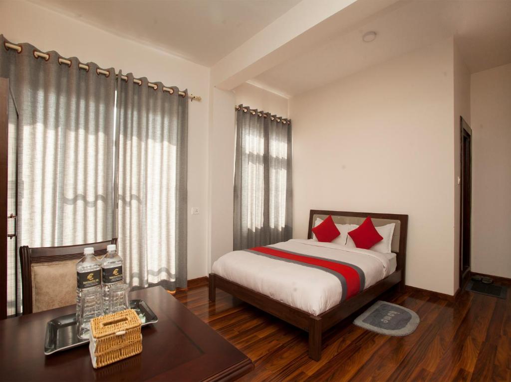 Hotel Euro في كاتماندو: غرفة نوم بسرير ومخدات حمراء وطاولة
