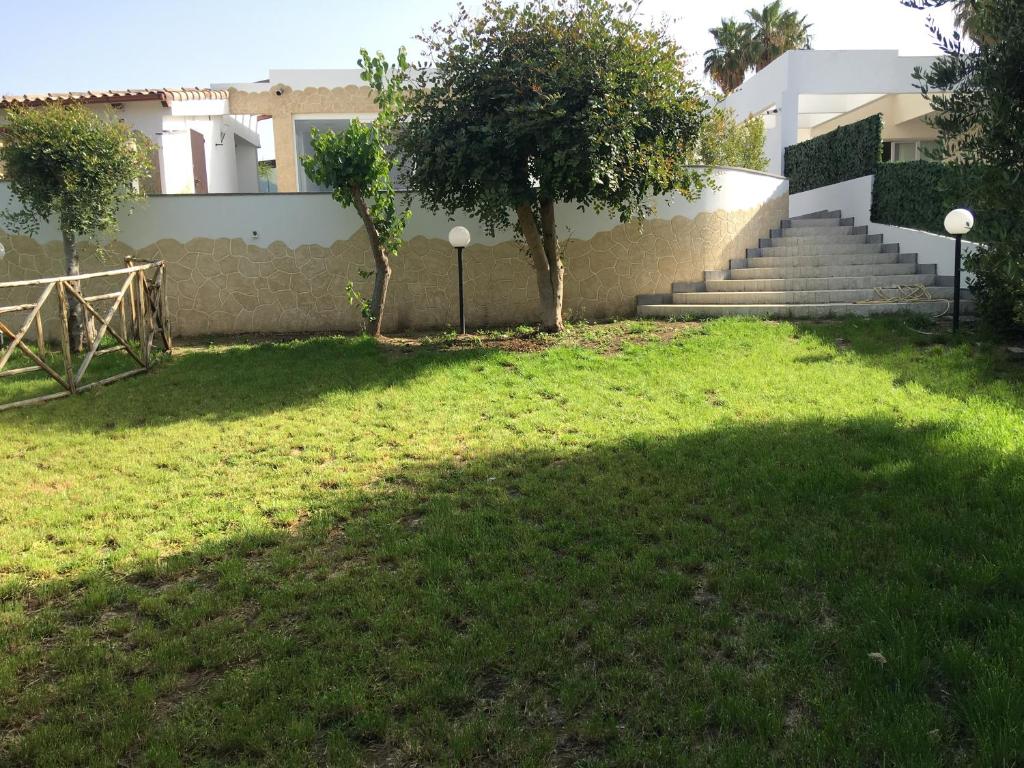 Ein Schatten eines Baumes auf dem Gras neben einem Gebäude in der Unterkunft Villa Relax giardino a Brucoli Siracusa e Catania in Brucoli