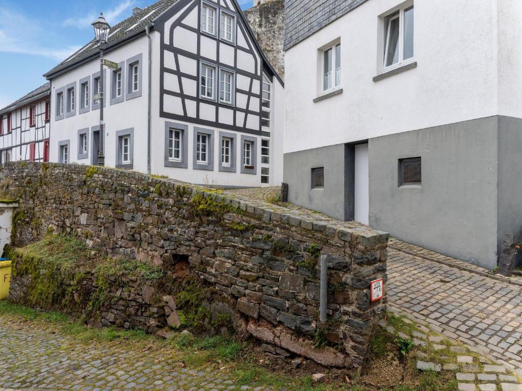 an old stone wall in front of two buildings at Modern Apartment in Reifferscheid with Garden in Hellenthal