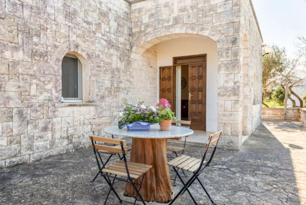 un patio con mesa y sillas frente a un edificio en Logement vue sur les oliviers, en Le Lamie di Olimpe