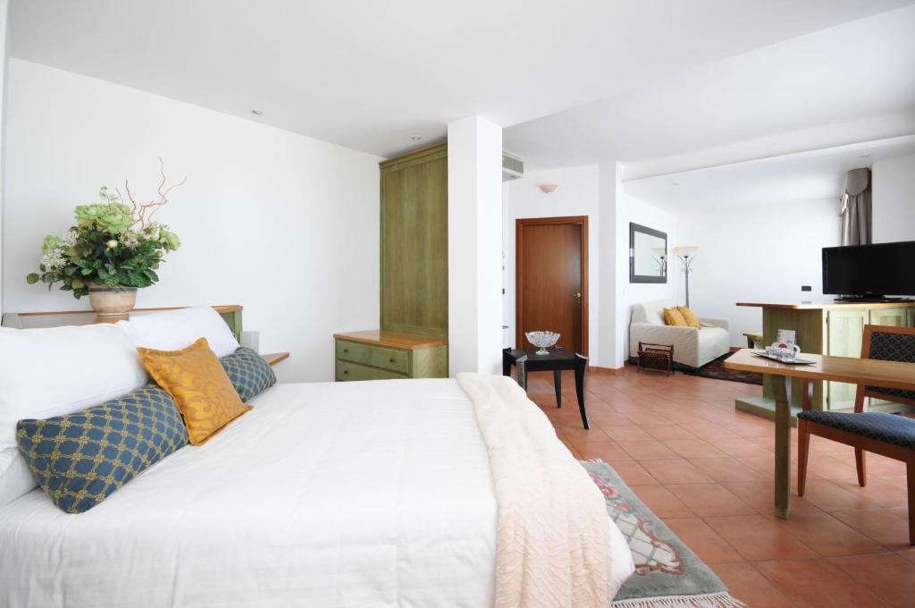 a bedroom with a white bed and a living room at Hotel Plaza in Lido degli Estensi