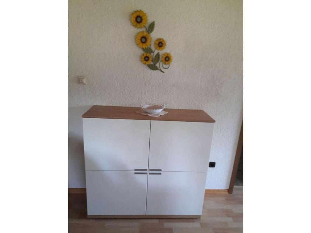 a white cabinet with a vase on the wall at Holiday apartment Schupp in Wittenschwand
