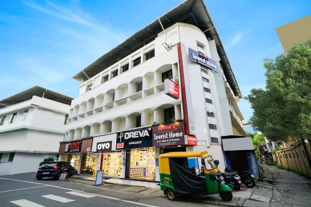 a white building with a scooter parked in front of it at OYO Flagship Arrows Tourist Home in Cochin