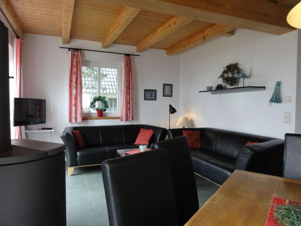 a living room with black leather couches and a table at Holiday home water view in Quilitz