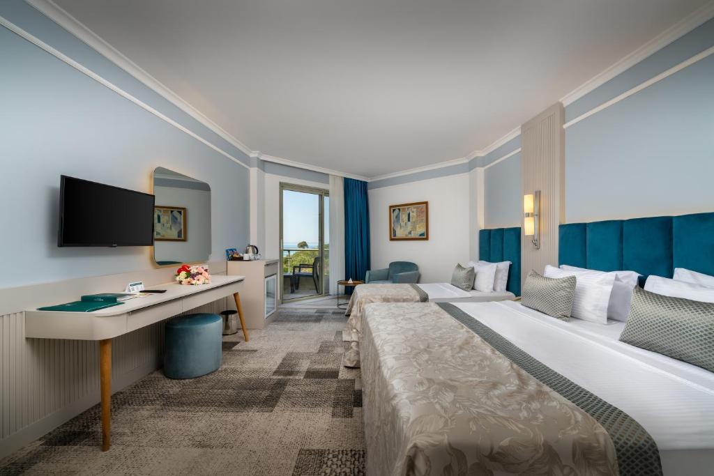 a hotel room with two beds and a desk at Pine Beach Belek in Belek