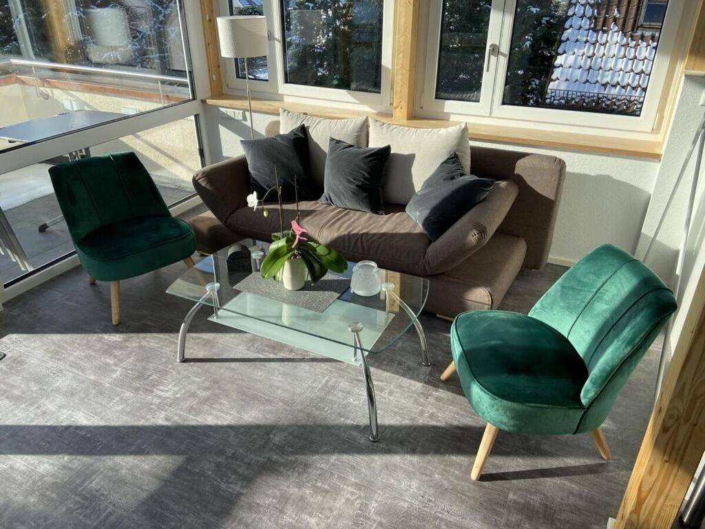 sala de estar con sofá y 2 sillas verdes en Holiday apartment feel-good time, en Markdorf