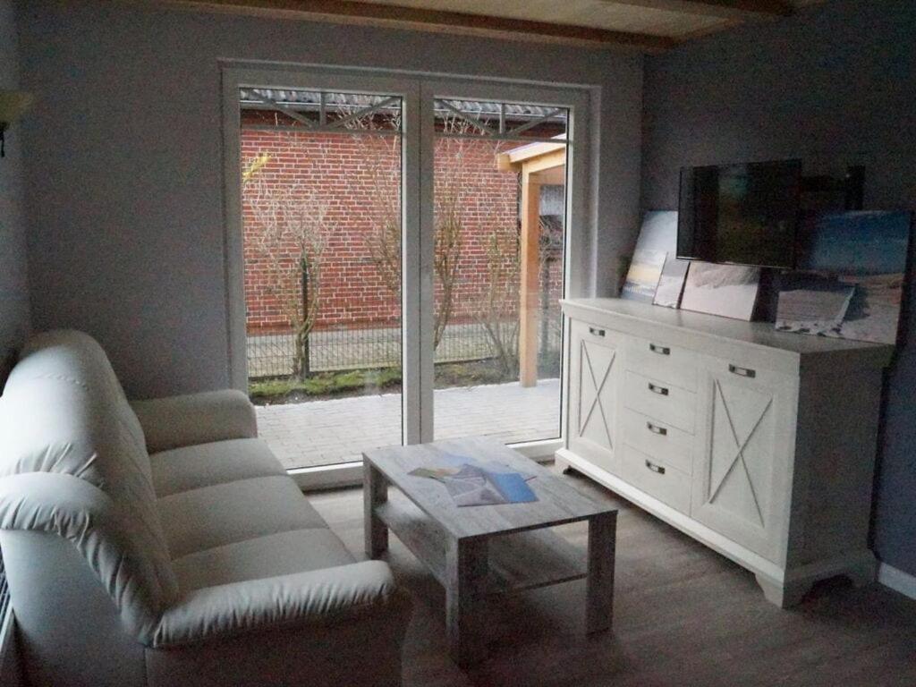 ein Wohnzimmer mit einem weißen Sofa und einem Fenster in der Unterkunft Holiday apartment Utholm in Tönning