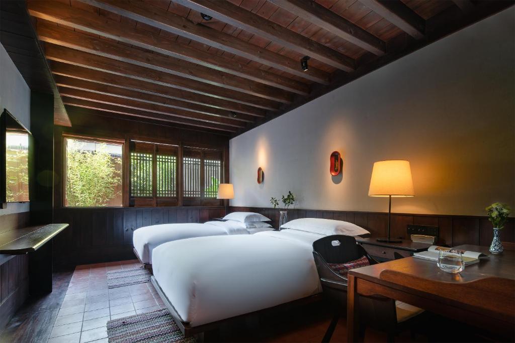 a bedroom with two beds and a table and a desk at Lijiang Ancient City Anyu Hotel in Lijiang