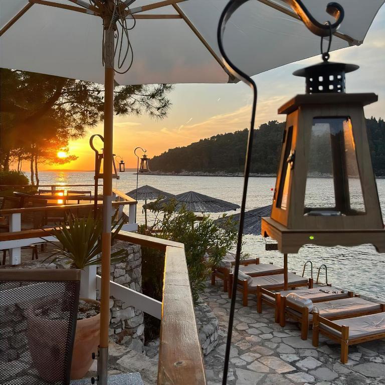 a group of benches on a beach with the sunset at Pebble Bay Paradise House in Vela Luka