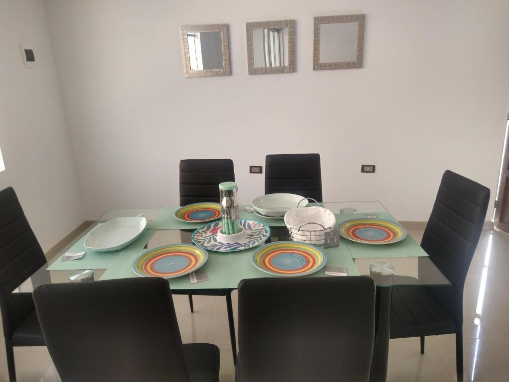 a dining room table with chairs and plates on it at Casa Hospedaje los Delfines en playa tortugas in Tortuga