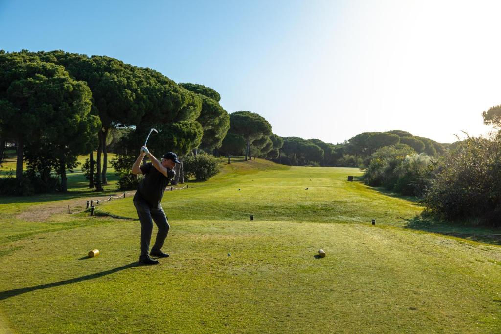 a man swinging a baseball bat on a golf course at Hotel Nuevo Portil Golf in El Rompido