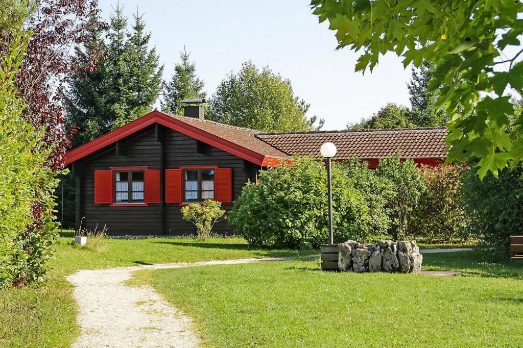a red and black house with a grass yard at Holiday homes Lauterd rfle Hayingen in Hayingen
