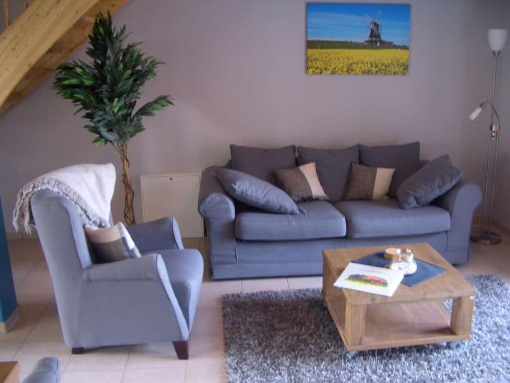 uma sala de estar com um sofá azul e uma mesa de centro em Seegarden on the Kastanienhof em Pellworm