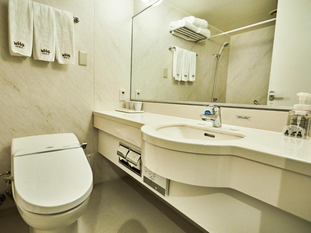 a white bathroom with a toilet and a sink at Kansai Airport Washington Hotel in Izumi-Sano