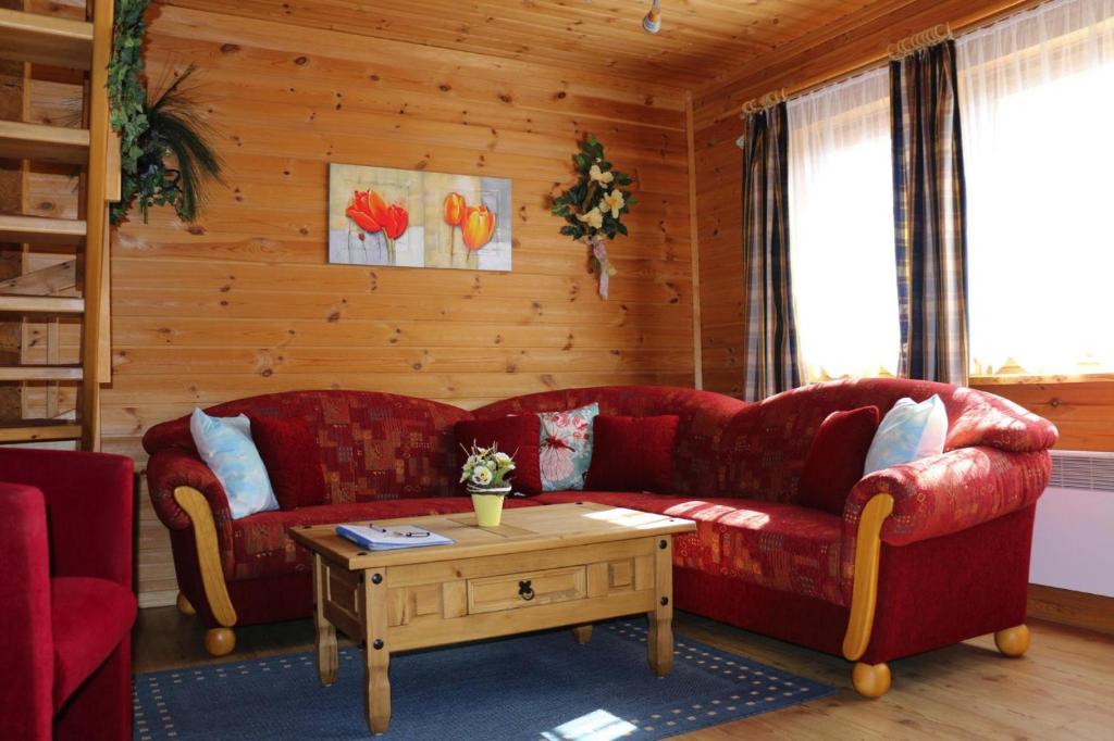 - un salon avec deux canapés rouges et une table dans l'établissement Blockhouse in the Fuchsbau Bad Sachsa, à Bad Sachsa