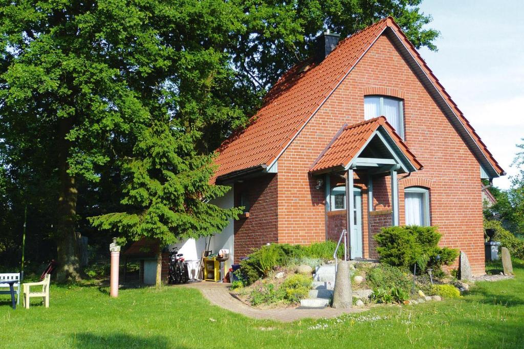 een rood bakstenen huis met een boom en gras bij Holiday home Plau am See in Plau am See