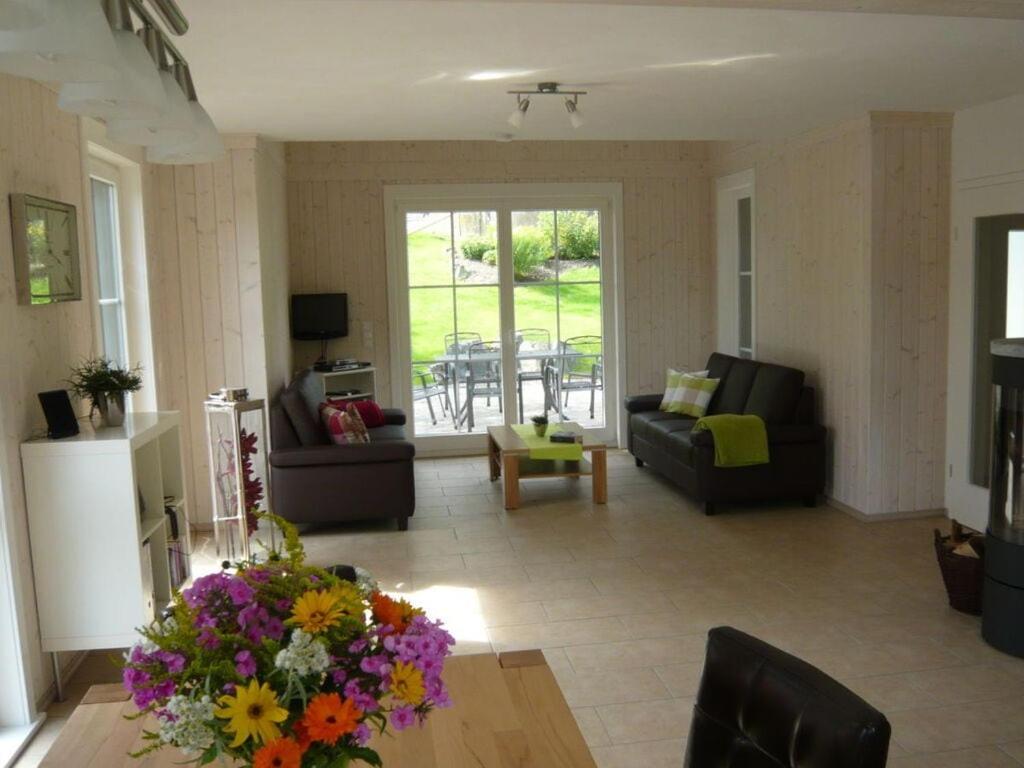 a living room with a couch and a table with flowers at Holiday home waterfall in Wasserfall