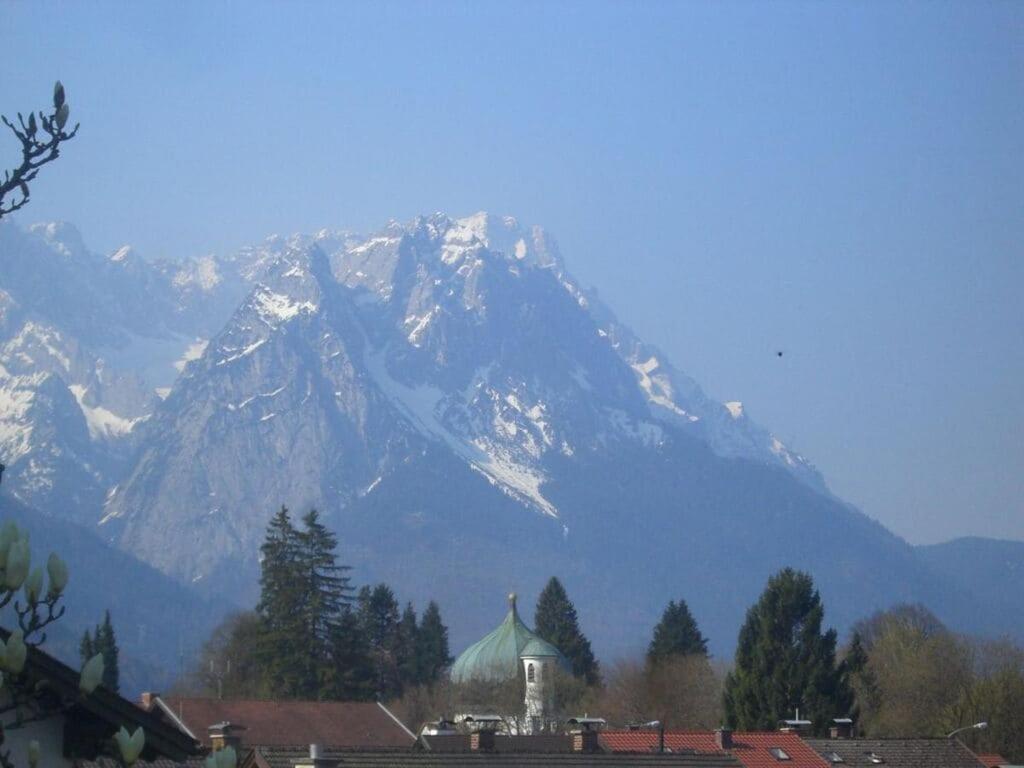 uma montanha coberta de neve com uma igreja em frente a uma cidade em Sunshine Apartment Anne em Garmisch-Partenkirchen