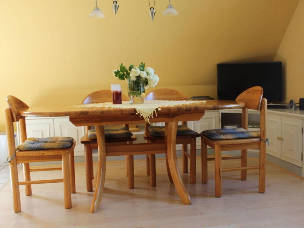 uma mesa de madeira com cadeiras e um vaso de flores em Holiday apartment in the marsh 2 em Ockholm