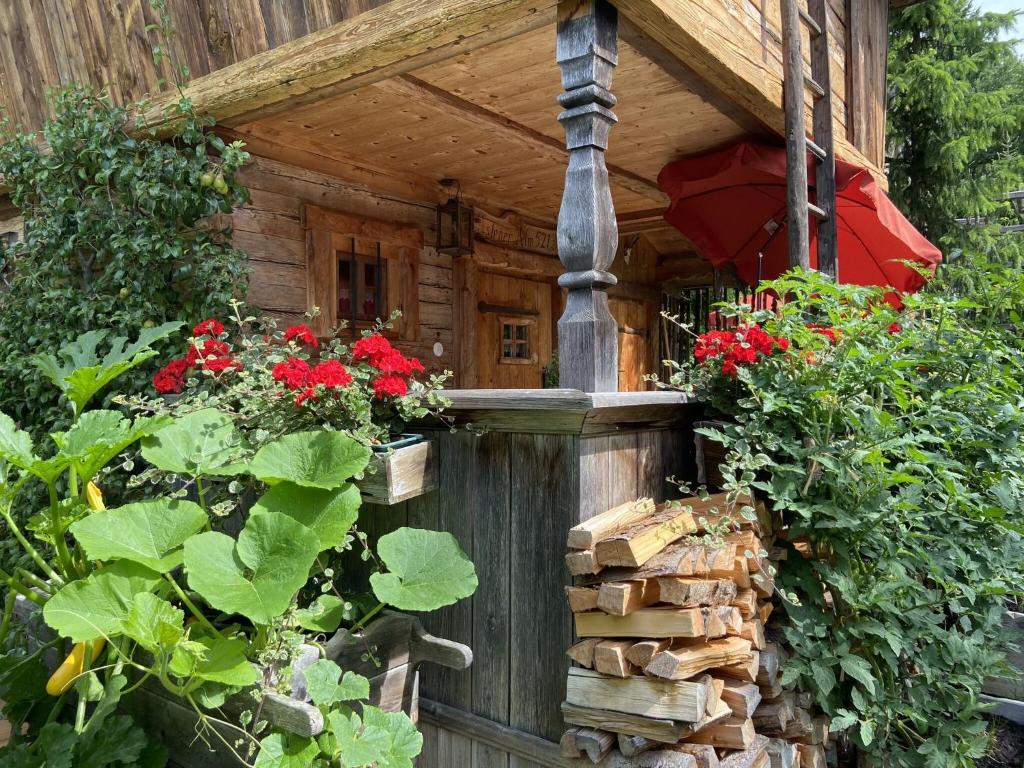 a wooden house with red flowers in the garden at Eco friendly chalet near the lake in Asten in Tittmoning