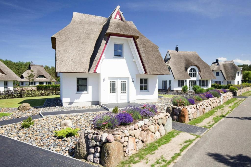 a cottage with a thatched roof and a stone wall at Holiday house Fuhlendorf in Fuhlendorf