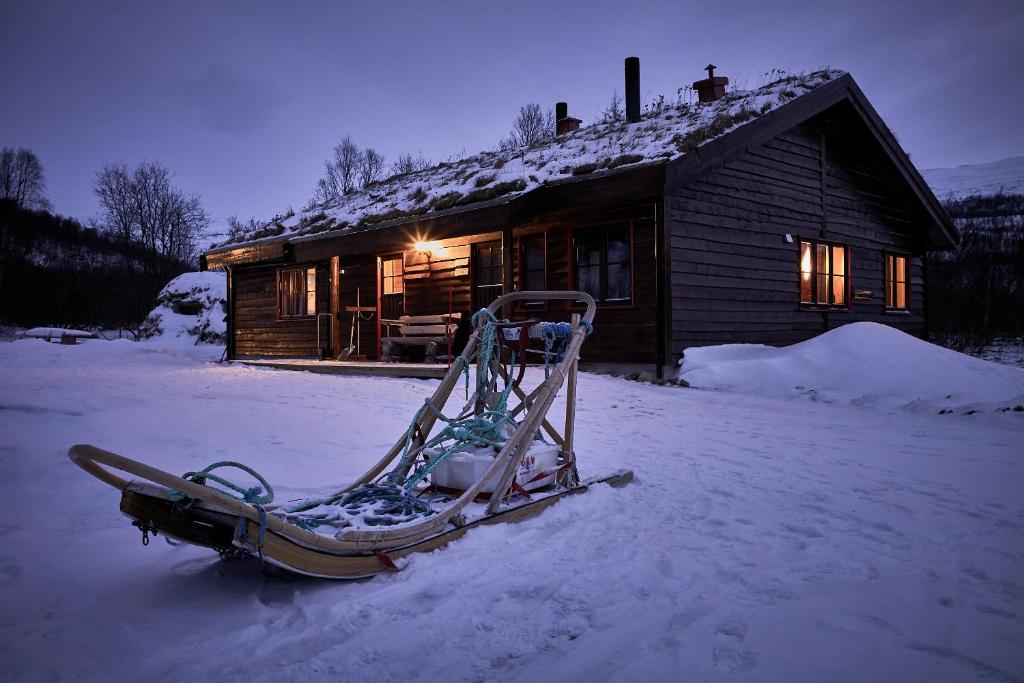 um trenó sentado na neve em frente a uma cabine em Cabin Huskyfarm Innset em Innset