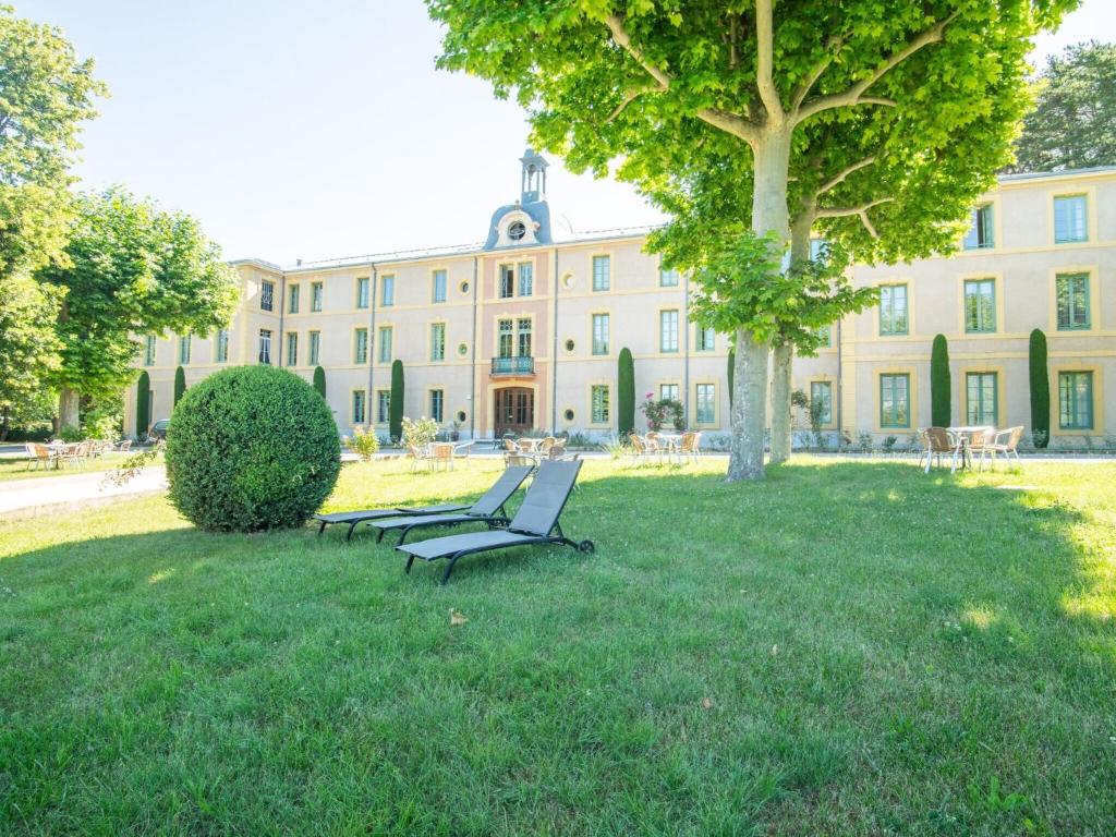 モンブリュン・レ・バンにあるCozy Apartment with Swimming Pool Terrace Garden Parkingの大きな建物前の公園ベンチ