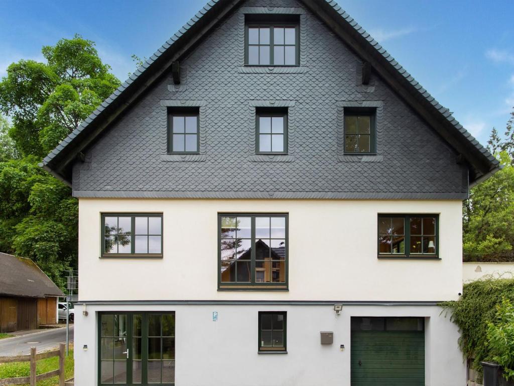Casa blanca con ventanas negras y techo gris en Spacious semi detached house with wood stove located directly on the Rennsteig, en Eisfeld