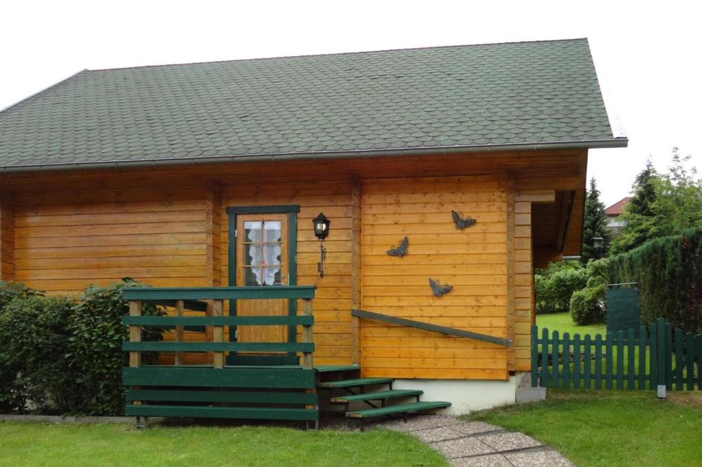 eine kleine Blockhütte mit einer Veranda und einem Fenster in der Unterkunft Blockhouse in the Fuchsbau Bad Sachsa in Bad Sachsa